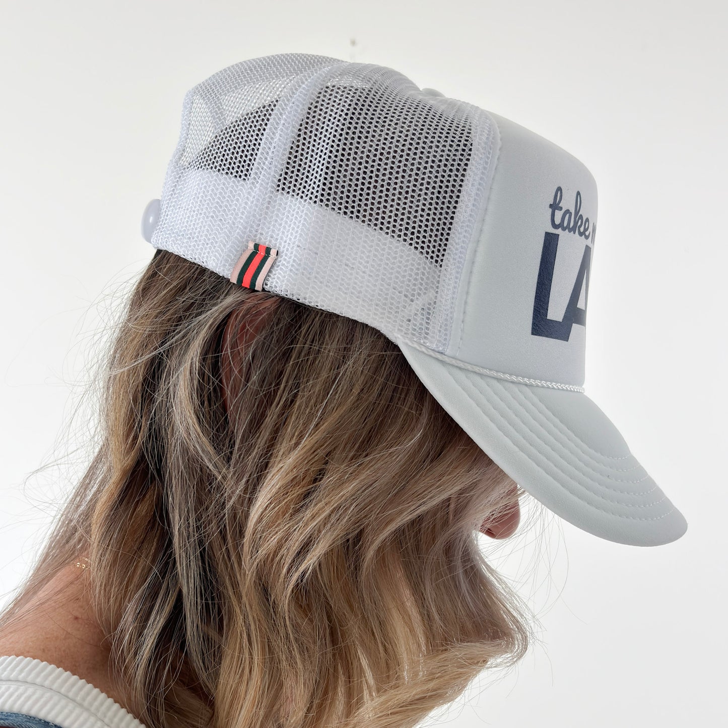 Women's white high profile foam snap back trucker hat with navy blue take me to the lake graphic