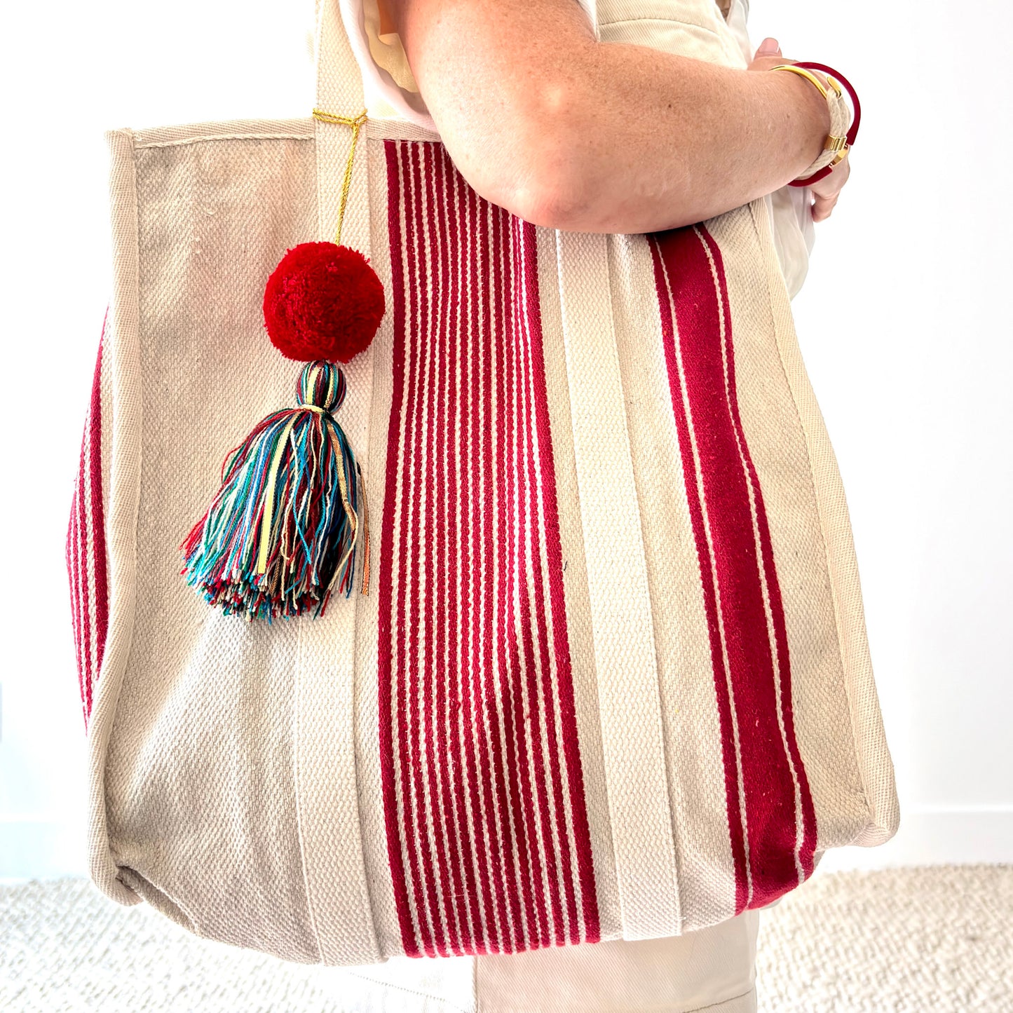 Natural canvas tote shoulder bag with red stripes and pom multi color tassel detail