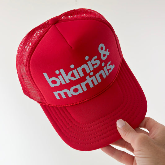 Women's bright red foam mid profile snap back trucker hat with blue bikinis & martinis. graphic
