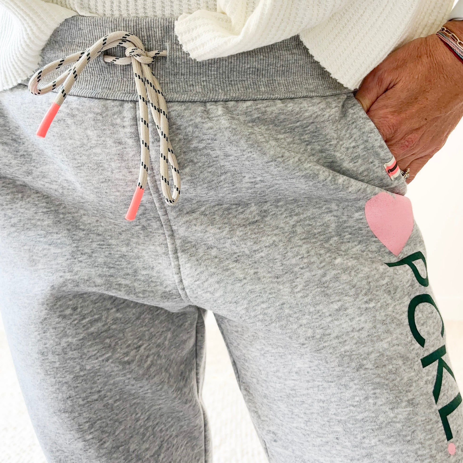 Women's light heather grey slim fit fleece jogger with pink heart and dark green pckl pickleball print.