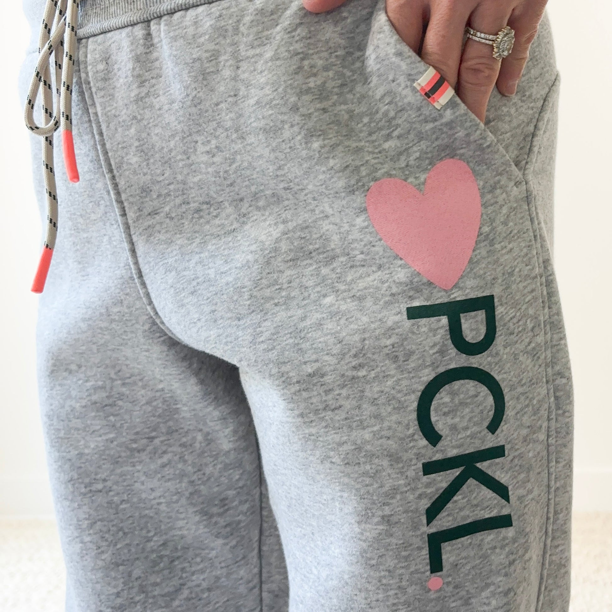 Women's light heather grey slim fit fleece jogger with pink heart and dark green pckl pickleball print.