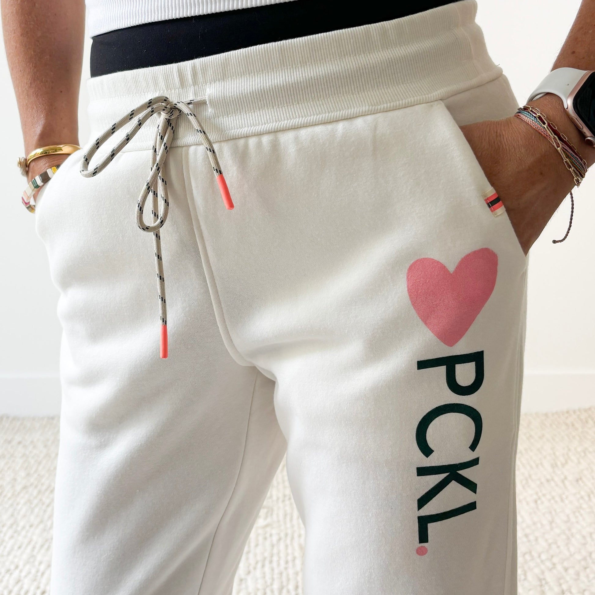 Women's ivory slim fit fleece jogger with pink heart and dark green pckl pickleball print.