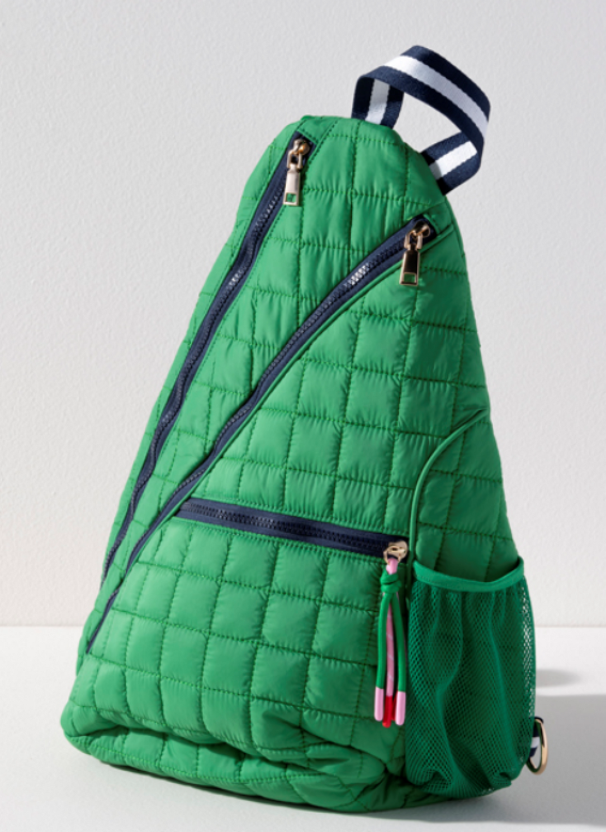 Kelly green quilted nylon tennis and pickleball sling backpack with navy zippers and navy white striped strap
