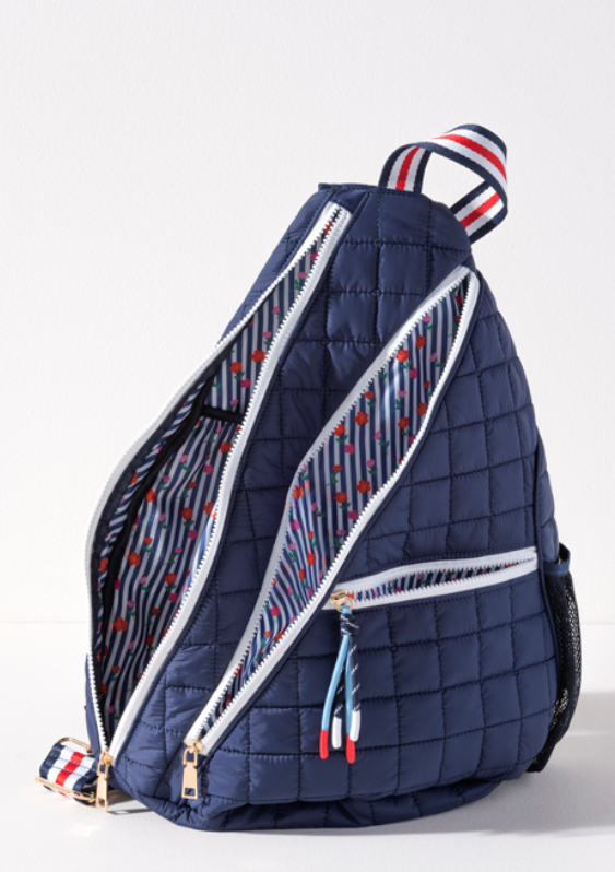 Navy blue quilted nylon tennis and pickleball sling backpack with white zippers and navy, red and white striped strap