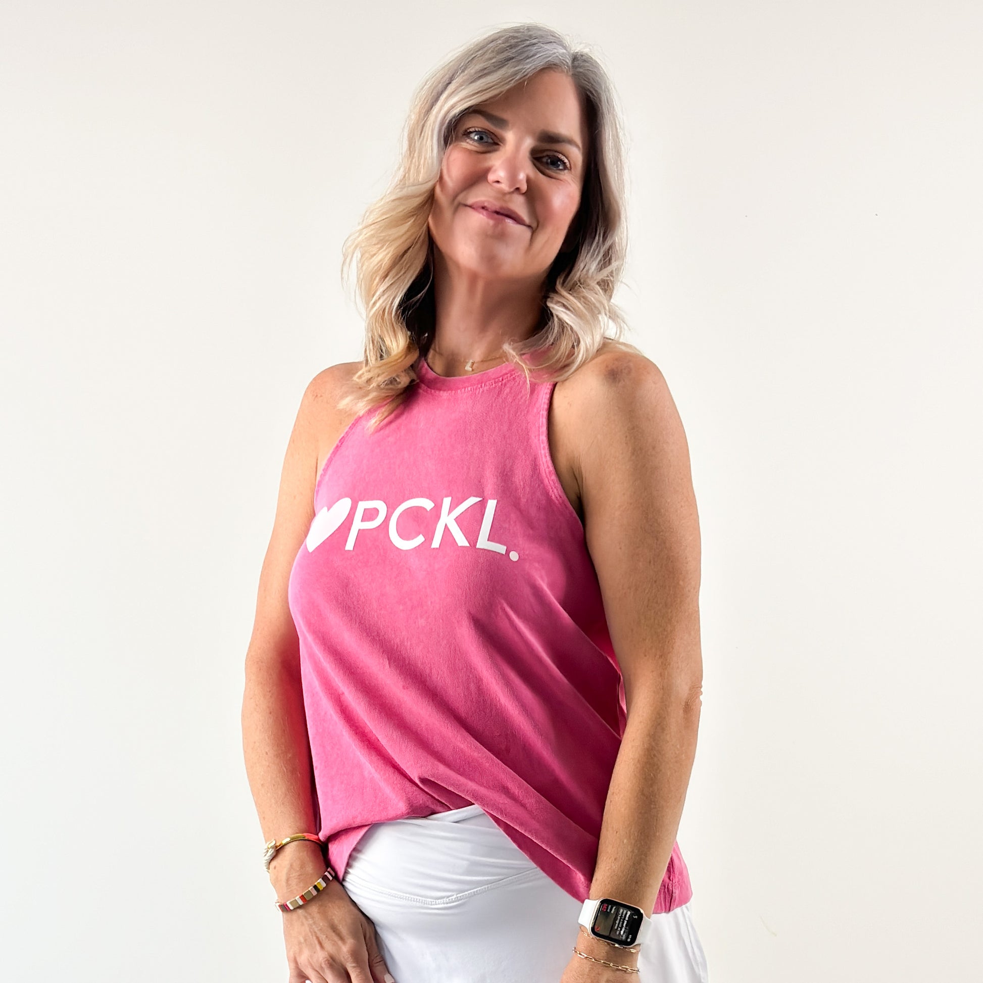 Women's bright pink swing fit racerback pickleball tank top with light pink heart and ivory pckl graphic