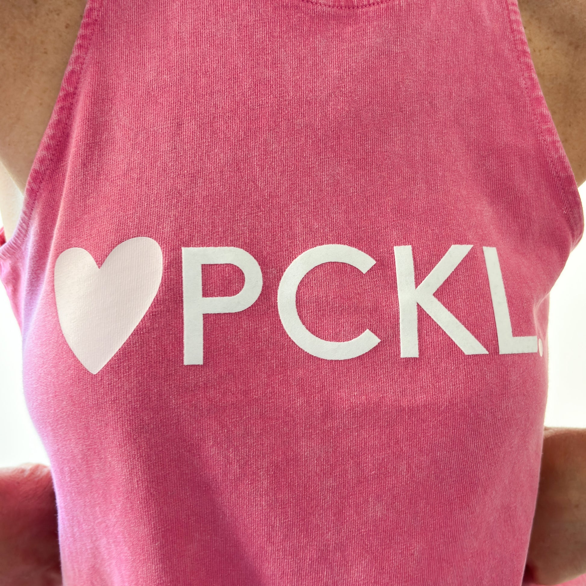 Women's bright pink swing fit racerback pickleball tank top with light pink heart and ivory pckl graphic